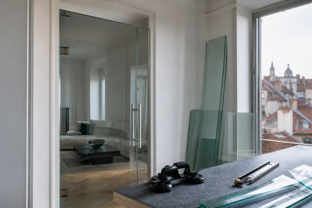 Porte en verre trempé transparente installée entre un couloir et un séjour